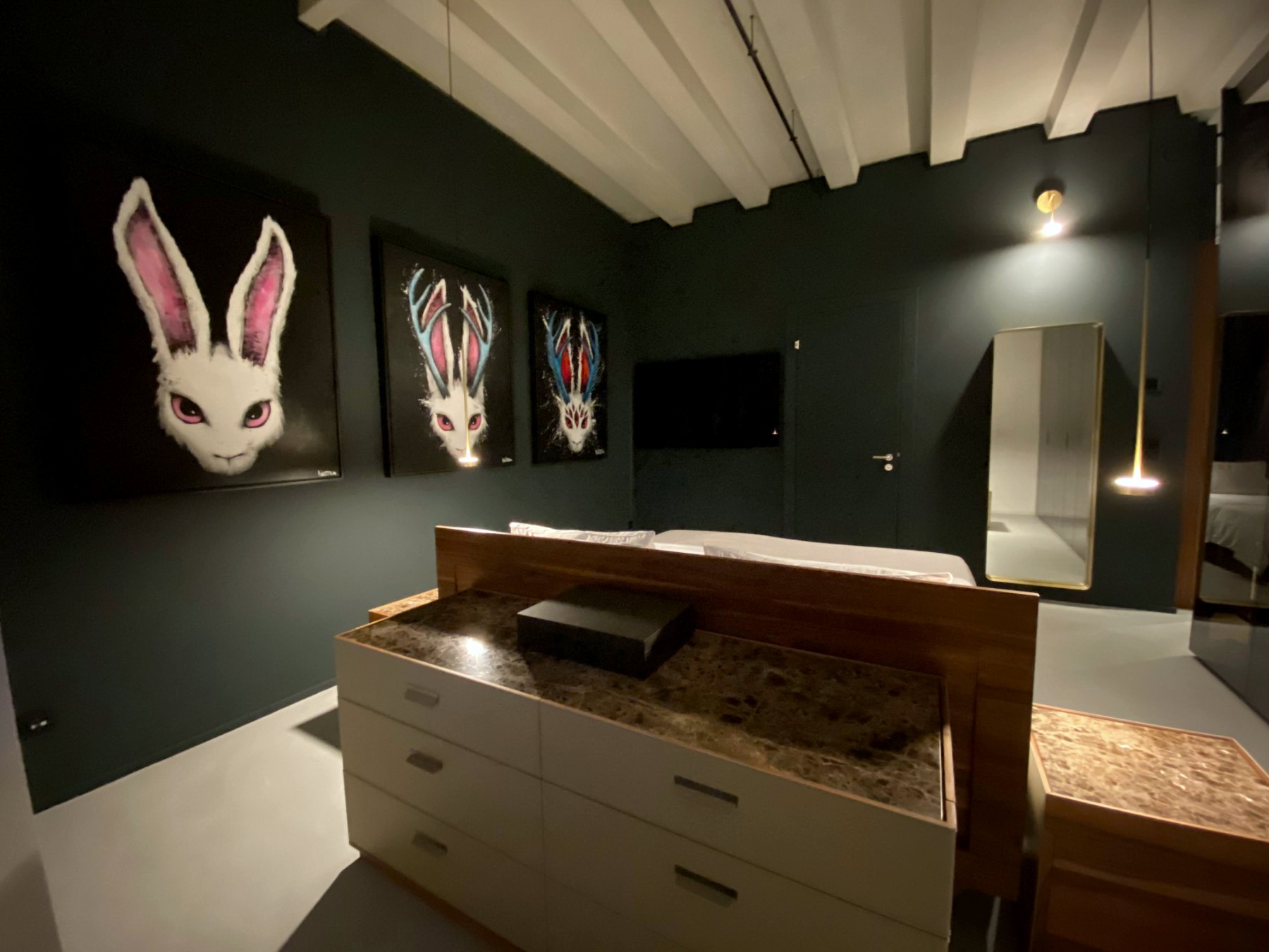 Master bedroom with deep green walls, walnut bed and three jackalope paintings